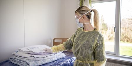Sundhedsfaglig medarbejder iført værnemidler som maske, forklæde og handsker. Foto: Kenneth Jensen.