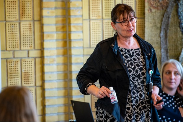 Anita Schlippe Rasmussen viser en flaske håndsprit mens hun forklarer kursusdeltagere om korrekt brug. Foto: Frederikssund Kommune, Kenneth Jensen.