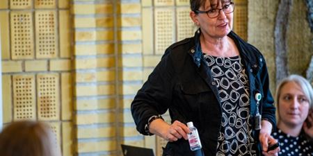 Anita Schlippe Rasmussen viser en flaske håndsprit mens hun forklarer kursusdeltagere om korrekt brug. Foto: Kenneth Jensen.