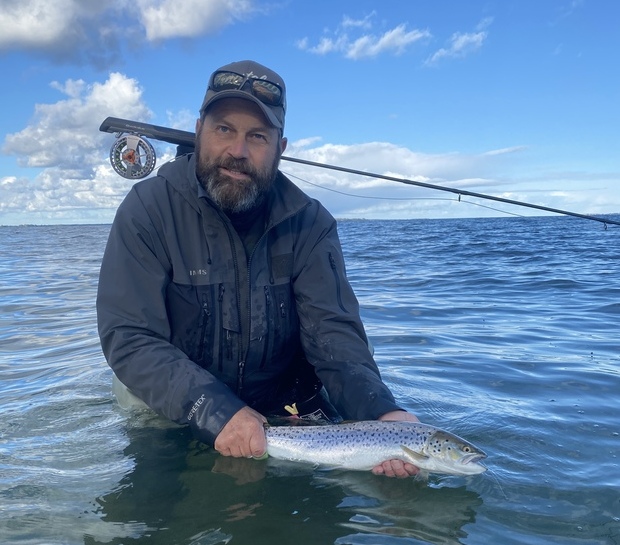 Lystfisker holder en blank ørred i vandoverfladen. Foto: Fishing Zealand.