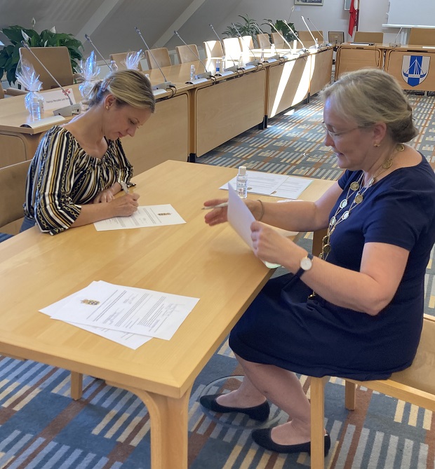 Kvinde underskriver papirer sammen med borgmesteren. Foto: Frederikssund Kommune.