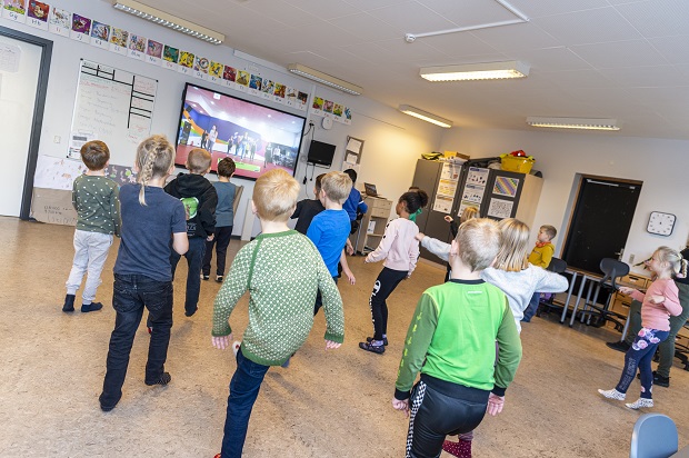 Børn danser mens de følger med på smart board hvor en video med dansen kører. Foto: Frederikssund Kommune, Kenneth Jensen.