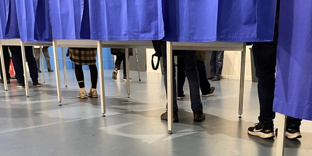 Vælgernes fødder ses under forhænget til stemmeboksene. Foto: Frederikssund Kommune. 