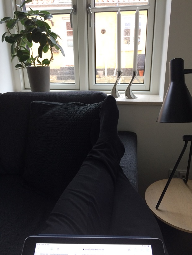 Et par ben ligger på armlænet af en sofa og i skødet ligger en tablet. Foto: Privatfoto