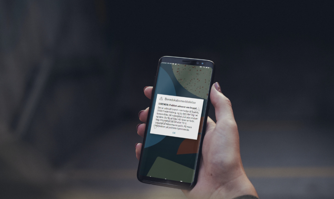 Hånd holder en mobiltelefon. Foto: Beredskabsstyrelsen.