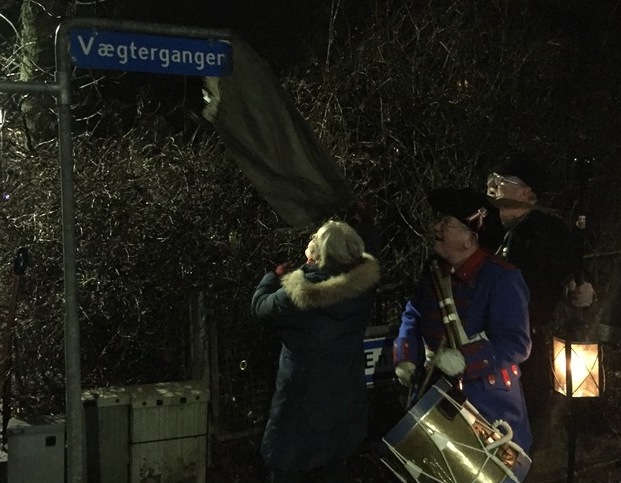 Borgmester Tina Tving Stauning (A) afslører skiltet med det nye vejnavn, mens en vægter spiller på tromme. Foto: Frederikssund Kommune.