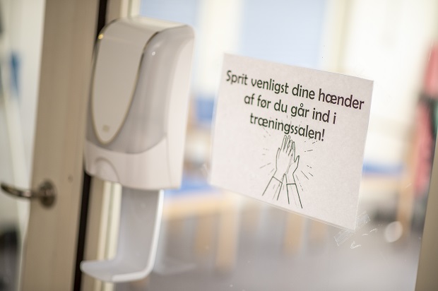 Skilt på dør, hvor der står: Sprit venligst dine hænder før du går ind i træningssalen. Foto: Frederikssund Kommune, Kenneth Jensen.