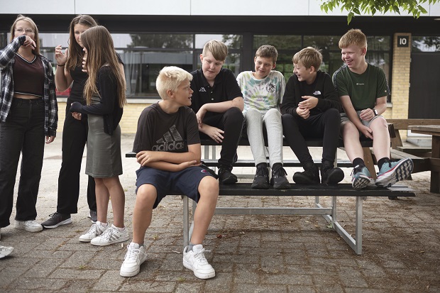 Børn og unge sidder på en bænk og snakker. Foto: Frederikssund Kommune.