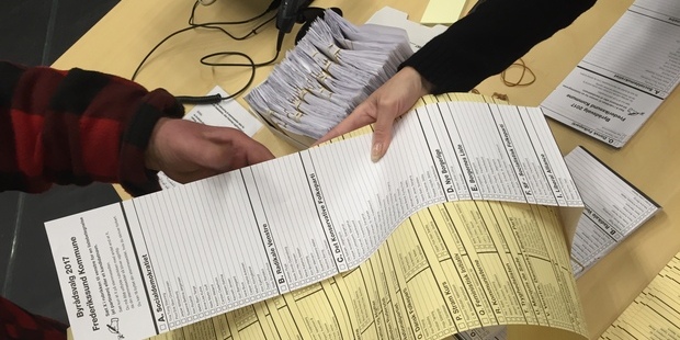 To stemmesedler udleveres til en vælger. Foto: Frederikssund Kommune.