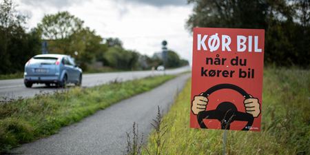 Plakat med kampagnebudskab langs en befærdet landevej. Foto: Rådet for Sikker Trafik.