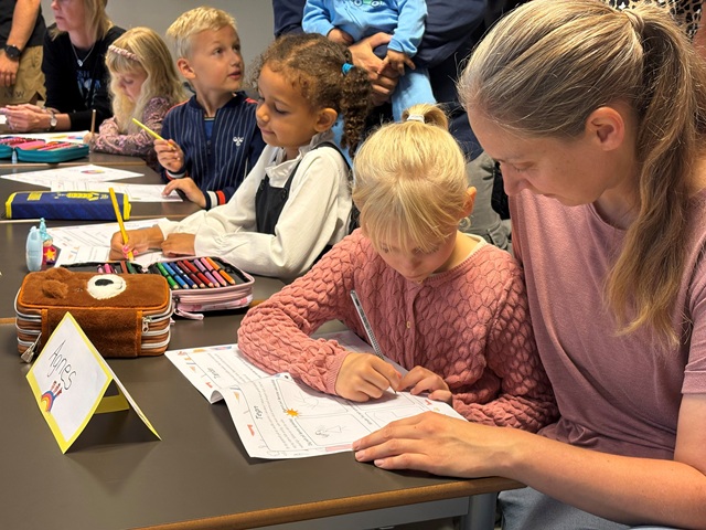 Mor og datter i forggrunden løser opgave, mens flere elever i baggrunden gør det samme. Foto: Daniel Sennek
