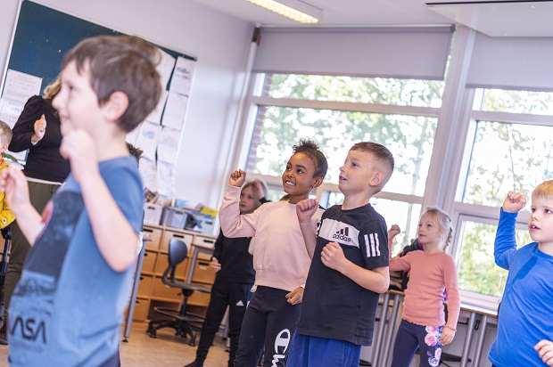 Børn danser og rækker højre arm op. Foto: Frederikssund Kommune, Kenneth Jensen.