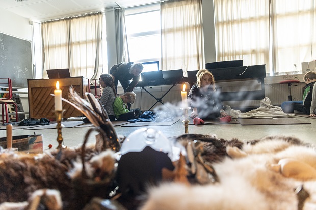 Yoga med røgelse og stearinlys i forgrunden og børn der laver øvelser i baggrunden. Foto: Frederikssund Kommune, Kenneth Jensen.
