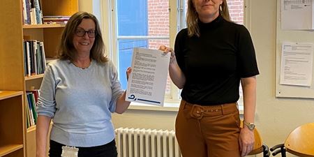 Mette Wittenburg og Trine Venbjerg Hansen med arbejdstidsaftale for pædagoger i folkeskolen. Foto: Frederikssund Kommune.