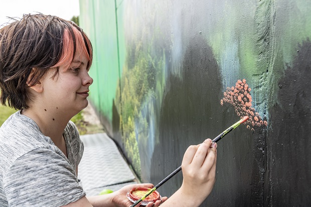 Amanda Troest maler blade på vægmaleri. Foto: Frederikssund Kommune, Kenneth Jensen.