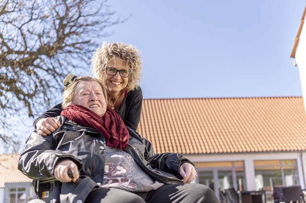 En ældre kvinde i kørestol og en yngre kvinde går sammen udendørs. Foto: Frederikssund Kommune, Kenneth Jensen.