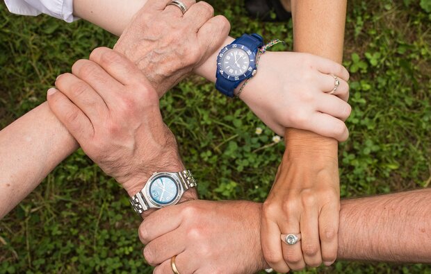 Fem hænder, der griber fat i hinanden om håndleddet så det dannes en femkant. Foto: Pixabay.