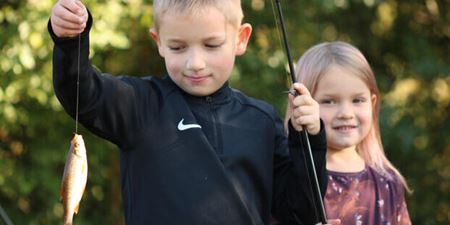En dreng og en pige holder en fiskestang med en fisk for enden af snøren. Foto: Fishing Zealand.
