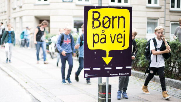 Plakat med ordene Børn på vej ved fortov med børn på vej til skole. Foto: Rådet for sikker trafik.