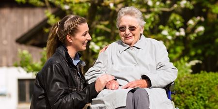 Ældre kvinde i kørestol - ung kvinde støtter hende omsorgsfuldt. Foto: Colurbox