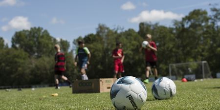 Fodbolde på græsplæne og fodboldspillere i baggrunden. Foto: Frederikssund Kommune, Kenneth Jensen.