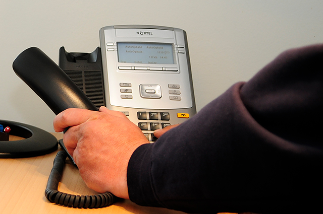 Du kan ringe til kommunen helt som normalt. Foto: Kenneth Jensen. Hånd har løftet røret på en fastnettelefon. Foto: Kenneth Jensen.
