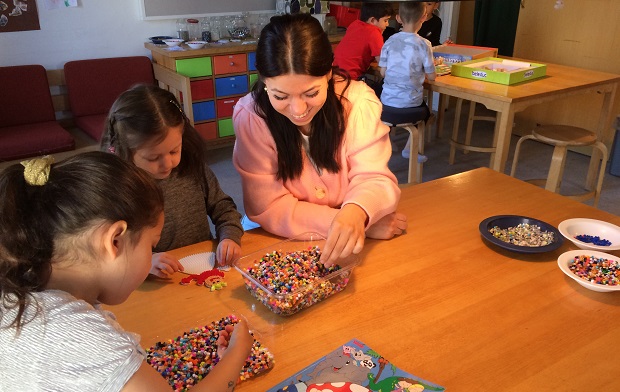 Børn og en voksen leger med perler og perleplader. Foto: Frederikssund Kommune.