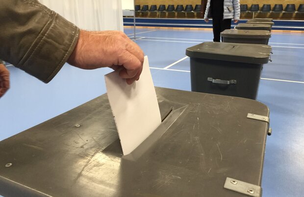 En hånd lægger en stemmeseddel i stemmeurnen. Foto: Frederikssund Kommune.