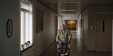 Ældre kvinde med rollator på en helt tom gang. Foto: Frederikssund Kommune, Kenneth Jensen.