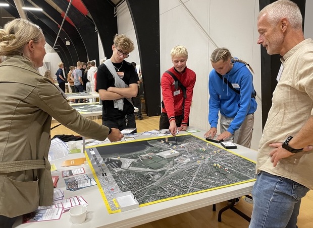 Fire personer står om et bord og kigger på et kort over Frederikssund midtby. Foto: Frederikssund Kommune.