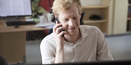 Medarbejder på kontor taler i telefon. Foto: Frederikssund Kommune.