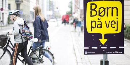 Børn på vej-kampagneplakat ved fodgængerovergang med krydsende cyklister. Foto: Rådet for Sikker Trafik.