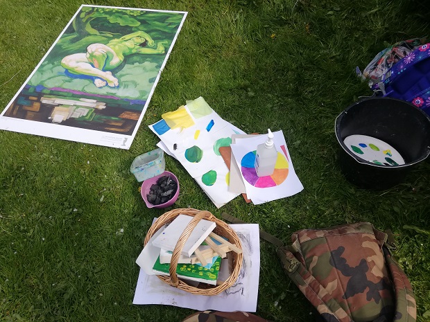 I græsset ligger forskellige materialer, farvercirkler og billedet Den grønne pige. Foto: Frederikssund Kommune.