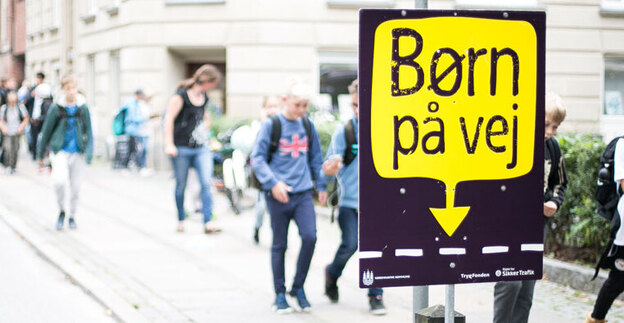 Skolebørn går ad fortovet. I forgrunden en kampagneplakat for "Børn på vej". Foto: Rådet for Sikker Trafik.