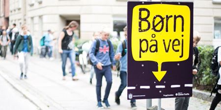 Skolebørn går ad fortovet. I forgrunden en kampagneplakat for "Børn på vej". Foto: Rådet for Sikker Trafik.