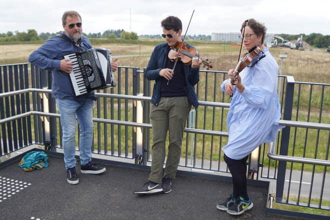 Peter Eget på harmonika (tv.), Marcus Mukherjee og Eva Sandfort på violiner spiller musik på Vinge Station. Foto: Jacques Duelund Mortensen.