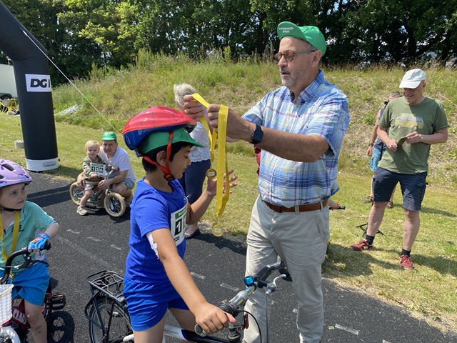 Udvalgsformand for Unge, fritid og idræt delte medaljer ud til børnene efter andet heat af børnecykelløbet. Foto: Frederikssund Kommune.