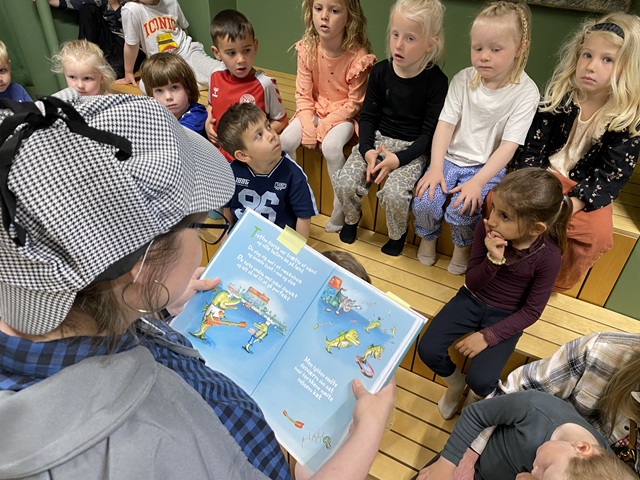 Sofie læser op fra en bog, mens børnene sidder og lytter. Foto: Frederikssund Kommune.
