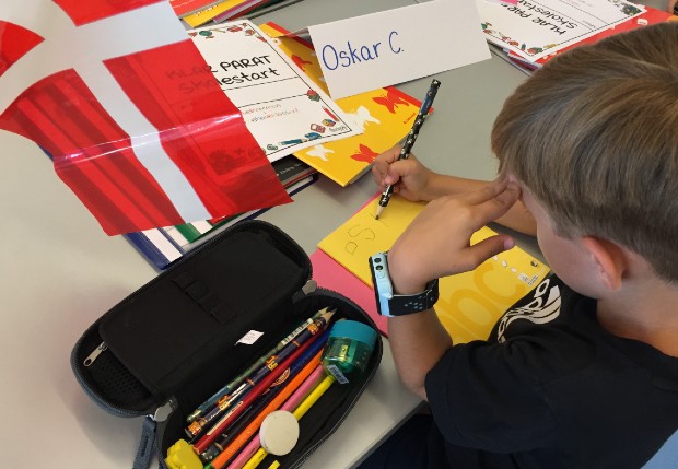 En elev er ved at skrive sit navn ind i skolebøgerne. Foto: Frederikssund Kommune.