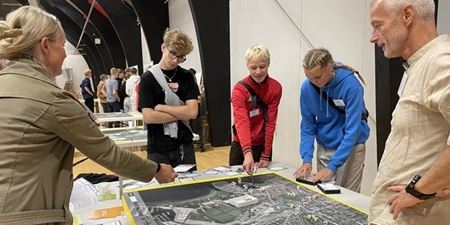 Fire personer står om et bord og kigger på et kort over Frederikssund midtby. Foto: Frederikssund Kommune.