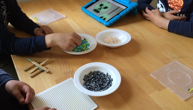 Børnehænder der leger med perler og perleplader. Foto: Frederikssund Kommune.