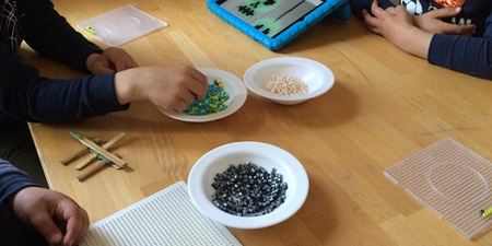 Børnehænder der leger med perler og perleplader. Foto: Frederikssund Kommune.