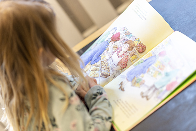 Pige sidder ved bord og læser i børnebogen Fru Strid. Foto: Kenneth Jensen, Frederikssund Kommune.