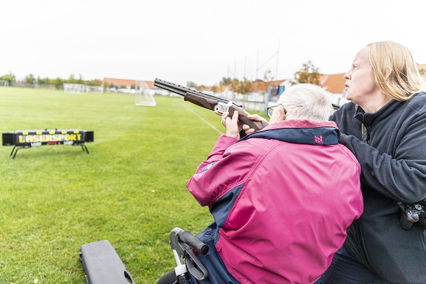 Kristian Larsen klar til at affyre geværet, mens en medarbejder hjælper med at holde geværet oppe. Foto: Frederikssund Kommune, Kenneth Jensen.