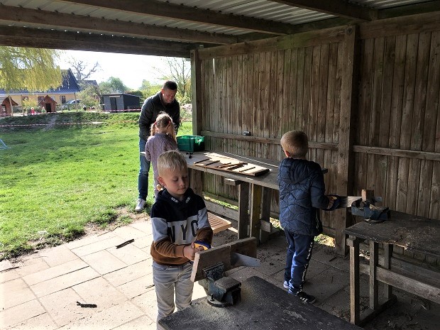 Tre børn og Morten Holst Nielsen arbejder med træ. Foto: Børnehuset Tumlebo