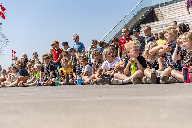 Børn fra SFO'en på Ådalens Skole venter tålmodigt på at få lov at lege på den nye Udendørs Gymnastiksal. Foto: Frederikssund Kommune, Kenneth Jensen.