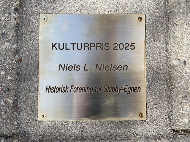 Plaketten i brostenene ved Langes Magasin med Niels L. Nielsens navn. Foto: Frederikssund Kommune.