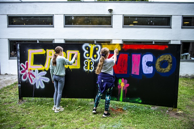 To piger maler på graffitivæg i haven ved Willumsens Museum. Foto: Frederikssund Kommune, Kenneth Jensen.