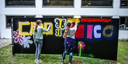 To piger maler på graffitivæg i haven ved Willumsens Museum. Foto: Frederikssund Kommune, Kenneth Jensen.
